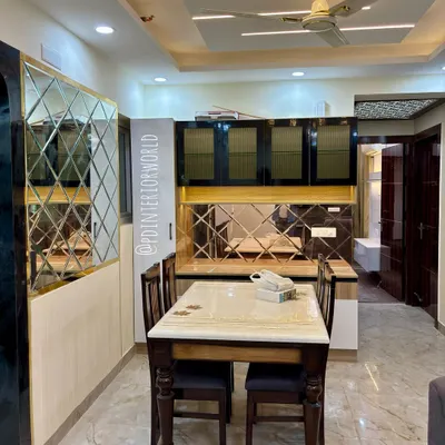 A dining area featuring a custom crockery unit with glossy black cabinets and a backsplash made of diamond-patterned mirrors.