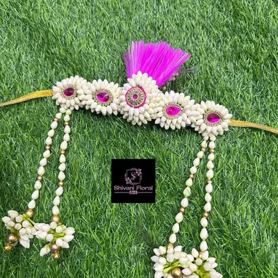 This is a fresh flower Bashing, a traditional head ornament worn by the bride and groom in Maharashtrian weddings. This piece is handcrafted from jasmine buds with pink accents and delicate pearl strings.