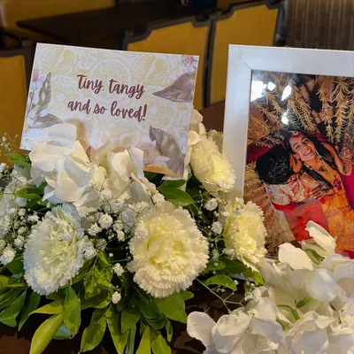 Personal touches make a celebration unique. For this citrus themed shower, a sweet photo of the couple was displayed alongside a custom card reading "Tiny, tangy and so loved," nestled in a bed of white carnations.
