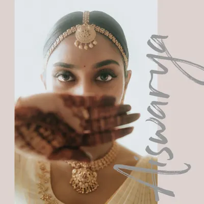 A creative portrait of the bride, Aishwarya, her face partially hidden by her mehendi-adorned hand, drawing focus to her expressive eyes.