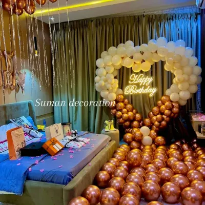 A surprise birthday decoration for a loved one in their bedroom. The setup includes a heart-shaped balloon arch, hundreds of balloons on the floor, and a "Happy Birthday" neon sign for a truly romantic gesture.