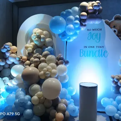 A cute teddy bear theme for a baby boy shower, with the message "So much joy in one tiny bundle". The setup uses a mix of blue, beige, and white balloons with soft lighting to create a warm and inviting look.