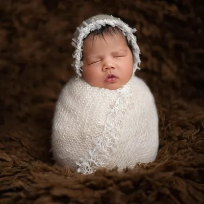 Perfectly swaddled and sleeping soundly. This classic newborn portrait, known as the potato sack pose, highlights the baby's peaceful features while ensuring they are snug, safe, and comfortable.