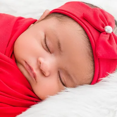 A close-up portrait of a sleeping baby girl, highlighting her soft cheeks and the sweet bow on her headband. These shots are about capturing the delicate and perfect features of your newborn in their first few days.
