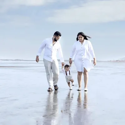 A beautiful family portrait taken during an outdoor session on the beach. The coordinated white outfits and the natural, expansive background create a serene and classic image of family togetherness.