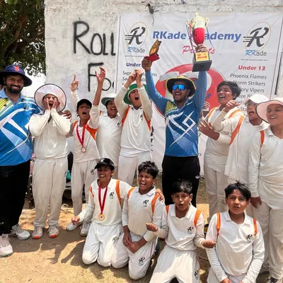 A moment of triumph for one of our winning teams. The coach and players celebrate together, lifting the championship trophy high, a symbol of their collective effort and success in the tournament.