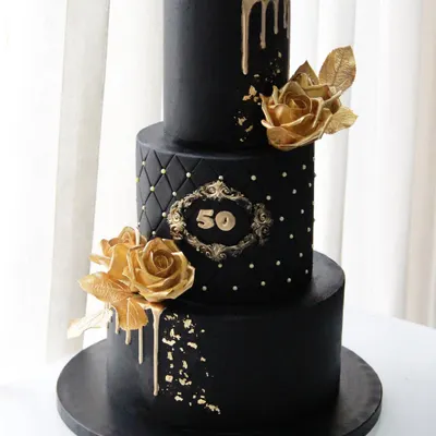 A 50th birthday deserves a statement piece. This dramatic three-tiered black and gold cake features a quilted middle tier, a custom monogram, and beautiful golden sugar roses.