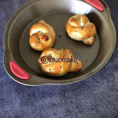 Freshly baked dinner rolls with a beautiful golden-brown crust and a sprinkle of nigella seeds. They are incredibly soft and fluffy, making them a wonderful addition to any meal.