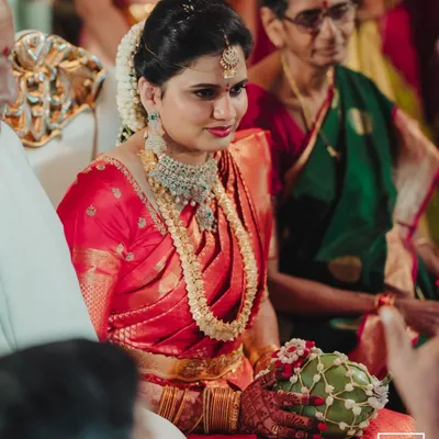 A candid portrait of a bride in a stunning red saree during her wedding ceremony, her expression full of gentle emotion.