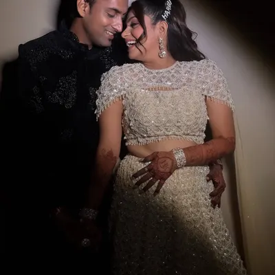 A candid, happy moment between the couple on their Sangeet night. The bride's makeup features a soft glam eye and glowing skin, perfect for looking radiant under the spotlight.