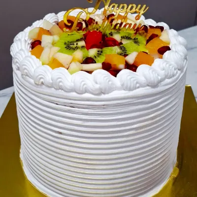 My fresh mixed fruit cake is a light and refreshing choice for any celebration. This eggless vanilla cake is frosted with whipped cream and topped with a colorful assortment of seasonal fruits like kiwi, pomegranate, and apple.