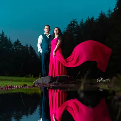 A dramatic pre-wedding shot by a lake at dusk. The flowing dress and its reflection in the water create a stunning, artistic image that tells a romantic story.