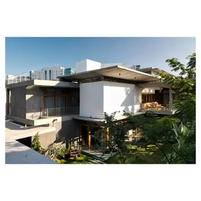 An exterior view showing the layered composition of concrete slabs and white volumes, nestled within the landscape.