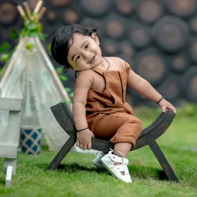 What a sweet pose! This little one looks so adorable in our garden, sitting on a rustic wooden bench with a teepee in the background.