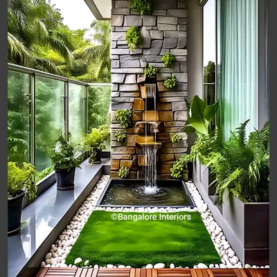 This is another take on a Zen balcony, featuring a stone waterfall set amidst lush ferns and greenery. The combination of wood deck tiles, artificial grass, and white pebbles creates a rich tapestry of natural textures.