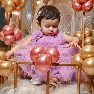 Capturing the curiosity of a one year old. This little girl is exploring her beautiful birthday setup, complete with pink and gold balloons.