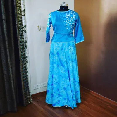 This Indo-Western set combines a modern crop top with a traditional flared skirt. The top has delicate white floral embroidery on one shoulder, while the blue tie-dye skirt adds a fun, bohemian feel to the ensemble.