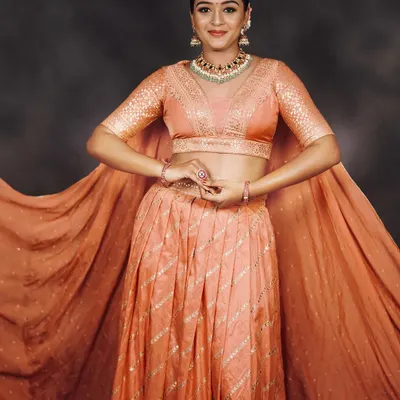 A graceful peach lehenga with cape-style sleeves. This outfit is light, elegant, and perfect for a sangeet, reception, or bridesmaid look.