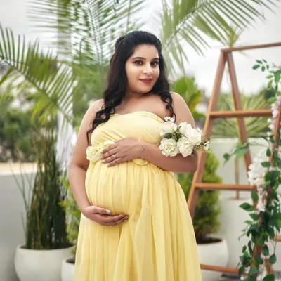 A glowing solo portrait in our strapless yellow floral gown. The client is holding a bouquet of white roses, adding a fresh and beautiful touch.