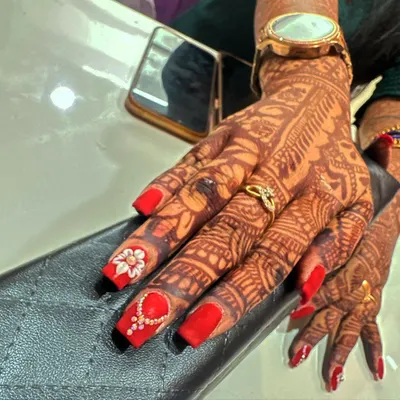 A classic bridal look featuring bold red nails that stand out beautifully against the dark mehndi stain. I added a 3D floral accent nail and another with a delicate, jewelry-inspired stone pattern.