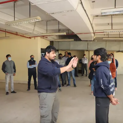 During an on-site corporate training session, I am explaining the importance of maintaining a safe distance from a potential aggressor. This foundational skill is crucial for preventing a physical confrontation.