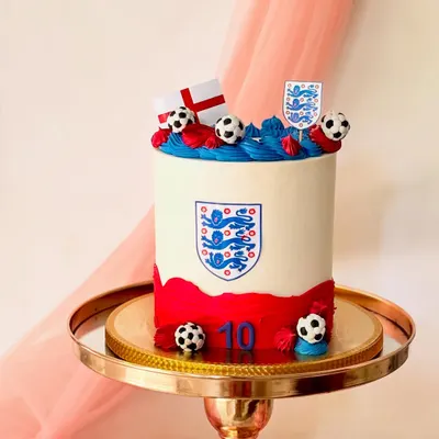 A cake for a fan of the England football team. This design features the team crest, the English flag, and fondant footballs on a clean buttercream base.