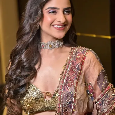 Mehandi, but make it couture. This look is about luxury without excess, featuring a flawless base, shimmering lilac eyeshadow, and soft curls to complement a high-fashion lehenga.
