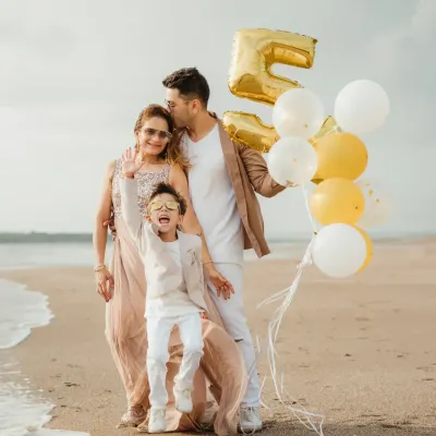 A family celebrates a "Fabulous 5" birthday on the beach, complete with balloons. The energy and joy in this shot are what beach photoshoots are all about.