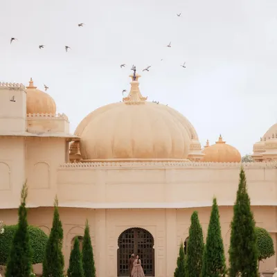 A moment of quiet solitude against the magnificent domes of The Oberoi Udaivilas in Udaipur. This wide, architectural shot makes the bride a part of the palace's grandeur, creating a truly regal and timeless portrait.