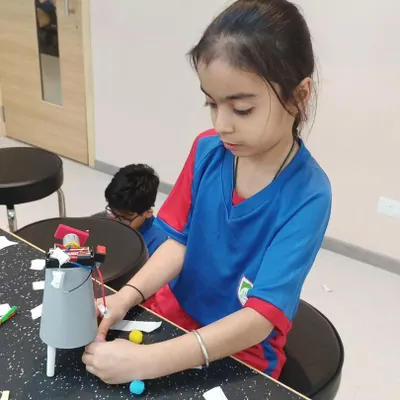 A young engineer focuses intently on assembling her robot. Each session encourages logical reasoning and provides hands-on building experience.