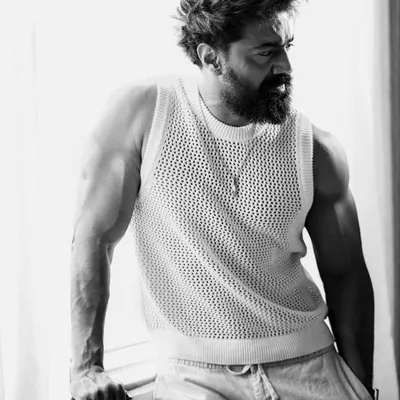 A powerful black and white portrait of actor Dev Adhikari. The high-contrast lighting carves out his muscular physique, creating a dramatic and intense image that highlights his physical transformation for a role.