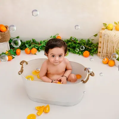 It's summertime. This little one is having a splash in a tub full of oranges and bubbles, a perfect way to capture a fun milestone.