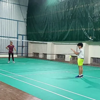 A coach provides shuttlecocks for a young player to practice his returns. Our one-on-one guidance during group sessions ensures every player gets personal attention.
