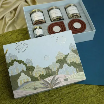 Our signature Diwali box, open to display a curated selection of treats. It includes jars of mixed dry fruits, chocolate brittle, cardamom, gourmet cookies, and two wooden diyas.