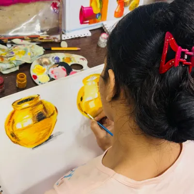 A student from our elementary exam batch perfecting her metal painting. She is learning to capture the reflections and highlights that make the object look realistic and three-dimensional.