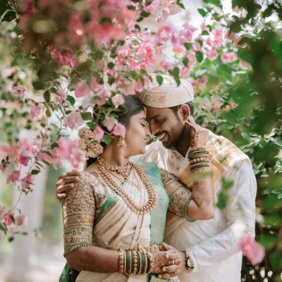 A tender moment shared between the couple, framed by beautiful pink bougainvillea. This style of natural, romantic portraiture is perfect for capturing the soft emotions of your South Indian wedding day.