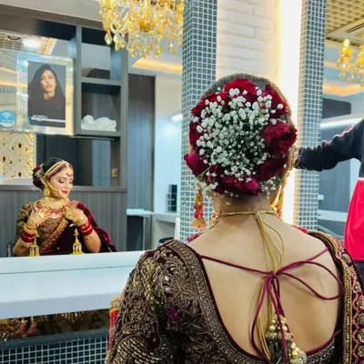 A close-up of a classic bridal hair bun. This intricate style is adorned with a combination of red roses and delicate gajra, perfect for a traditional wedding ceremony.