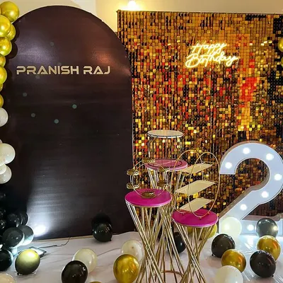 A glamorous 23rd birthday setup in black, white, and gold. This decor features a gold shimmer wall, a personalized backdrop, a neon "Happy Birthday" sign, and large light-up marquee numbers.