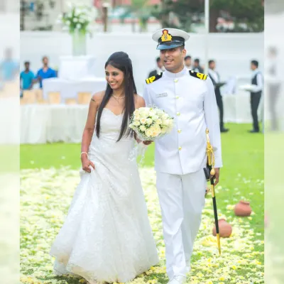 A beautiful Christian wedding procession, with the bride in a stunning white gown and the groom in his naval uniform, walking down an aisle of petals.