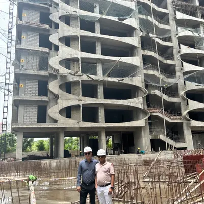 Our commitment to the client is paramount. Here, our principal architect is on-site with the client, overseeing the construction progress of a residential tower with a unique, curved facade to ensure every detail aligns with the vision.