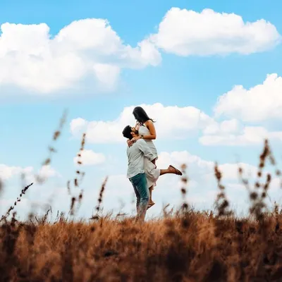 A classic romantic lift against a bright blue sky, capturing a feeling of pure joy and freedom. This outdoor pre-wedding shot showcases our love for wide, scenic compositions.