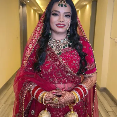 A full portrait of our beautiful bride who chose an open hairstyle for her D-Day. The classic red lehenga and bold lip create a timeless wedding look.