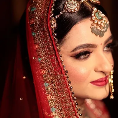 A close-up of our stunning bride. I focused on creating sharp, winged eyeliner and bold red lips to complement her traditional jewelry and create a look of pure royal elegance.