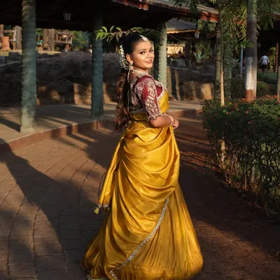 A beautiful back view of the yellow half-saree, showing the detailed embroidery on the blouse and the traditional hairstyle adorned with flowers.