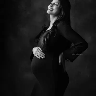 A portrait filled with pure joy, as the mom-to-be smiles with her eyes closed. The black and white format emphasizes her radiant expression.