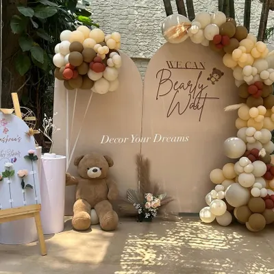 A modern and chic "We Can Bearly Wait" teddy bear themed baby shower. This setup features arched backdrops, a neutral-toned balloon garland, and a cute welcome board.