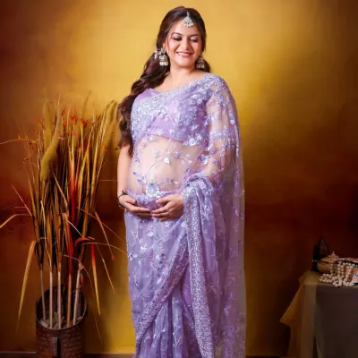 A full-length portrait showcasing a mom-to-be in a stunning lavender saree. Her joyful smile and the traditional attire create a beautiful and classic maternity photo.