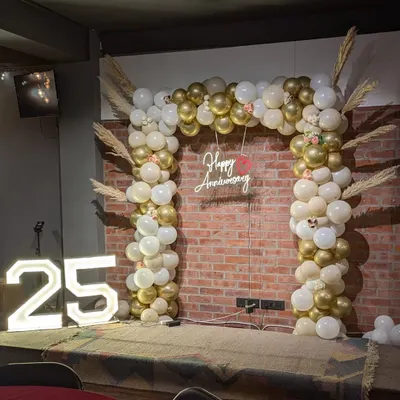 A full view of the 25th anniversary stage setup, featuring the gold and white balloon arch, 'Happy Anniversary' neon sign, and large '25' marquee numbers.