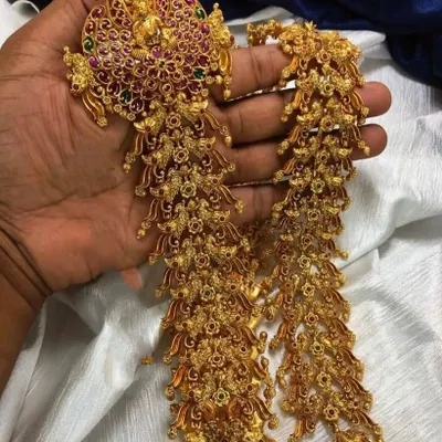 This is a traditional jade bille, a hair accessory used to decorate a long braid for a bridal look. This intricate, multi-piece ornament is available for rent to complete your muhurtham hairstyle.