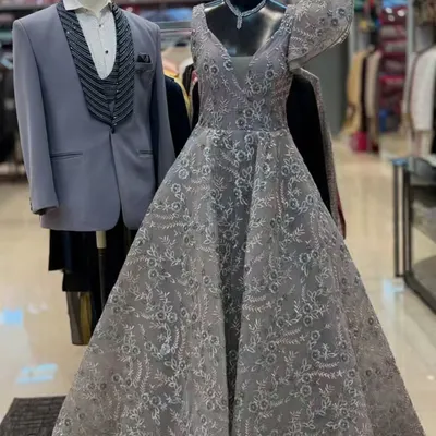A beautiful grey gown with intricate lacework displayed next to a matching grey three-piece tuxedo. This is a perfect pairing for a reception or engagement party.